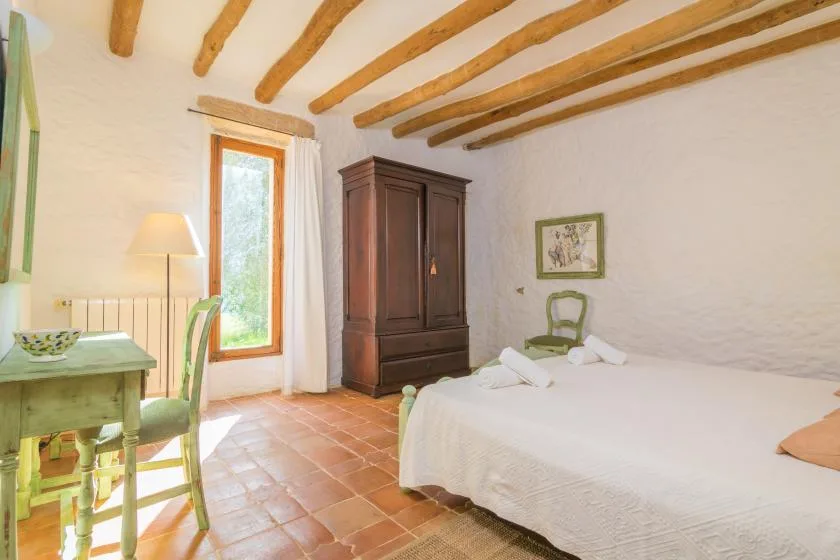 Un dormitorio con una cama grande, un armario de madera y vigas expuestas en el techo.