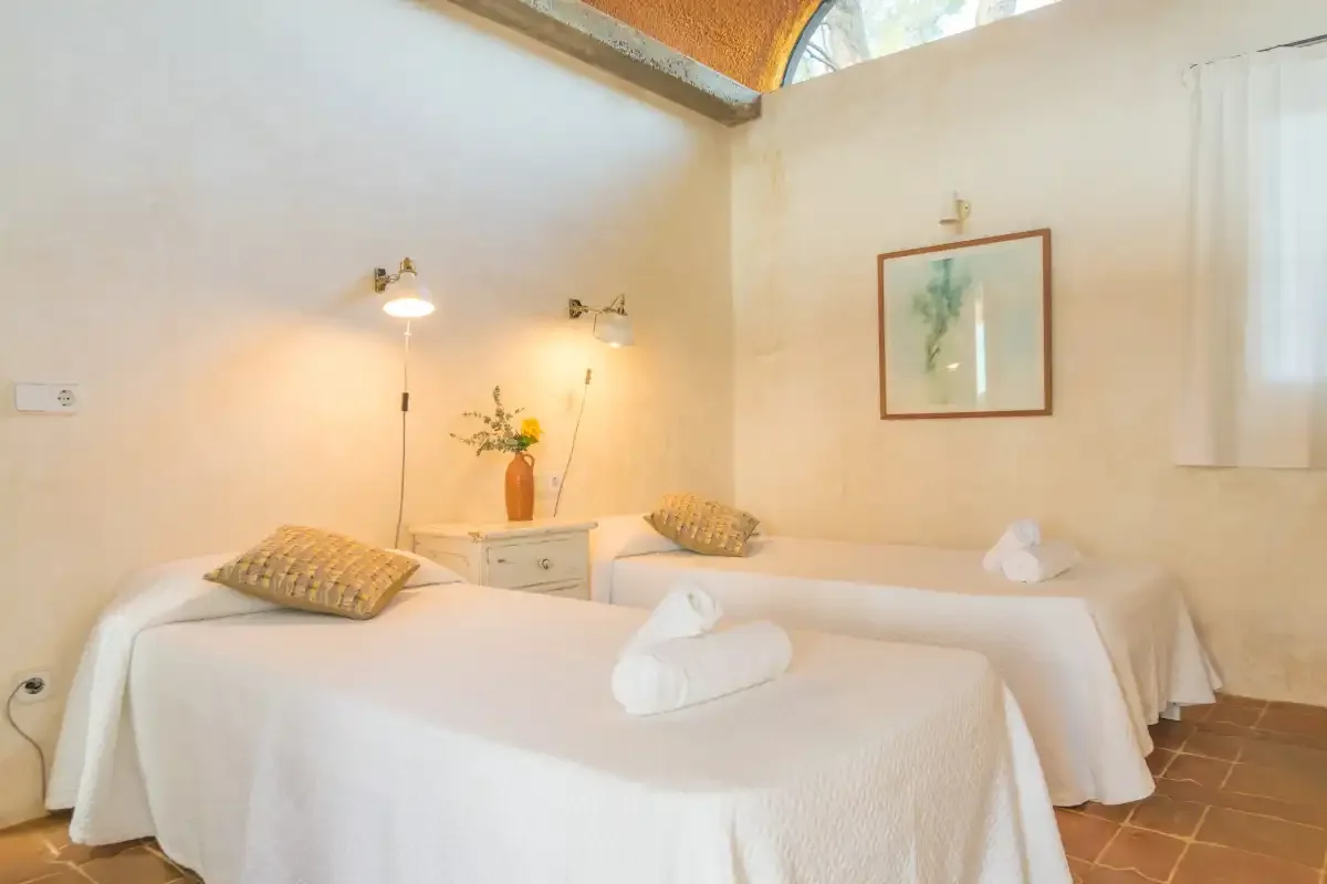 Una sala luminosa de tratamientos con dos camillas y un cuadro botánico.