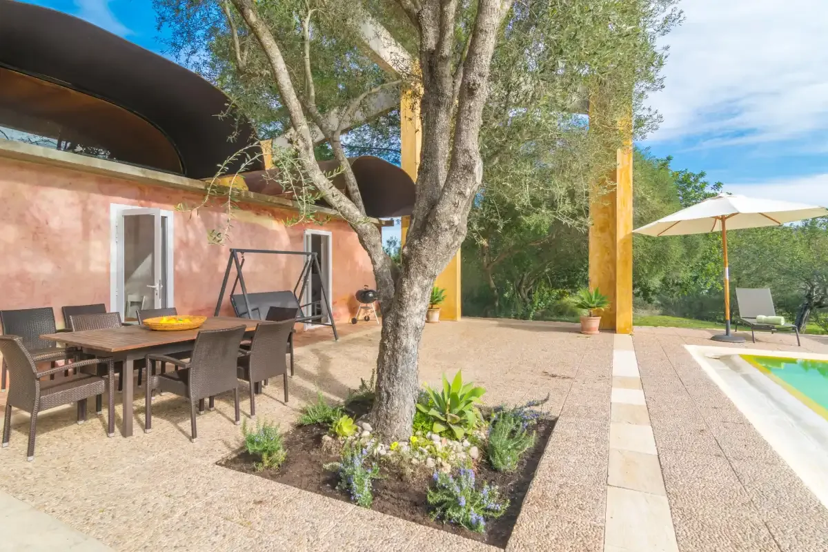 Patio exterior con asientos de comedor, un árbol y una piscina.