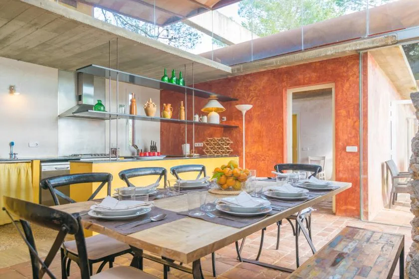 Un comedor con la mesa puesta junto a una cocina y estantes abiertos.