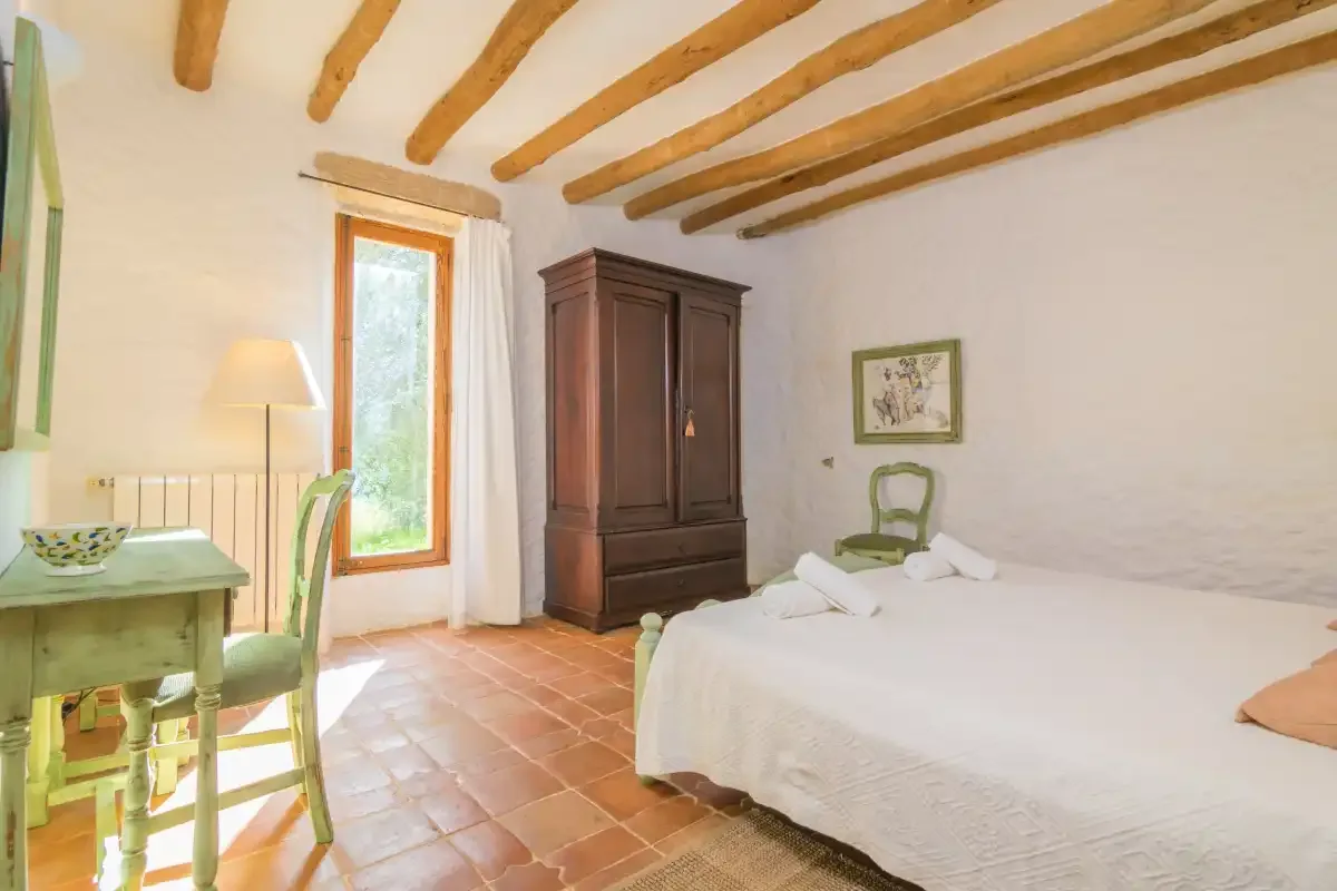 Un dormitorio con una cama, un armario de madera y vigas vistas en el techo.