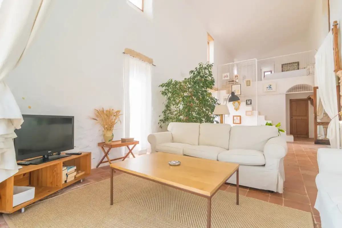 Una sala de estar luminosa con un sofá, televisor y mesa de centro de madera.