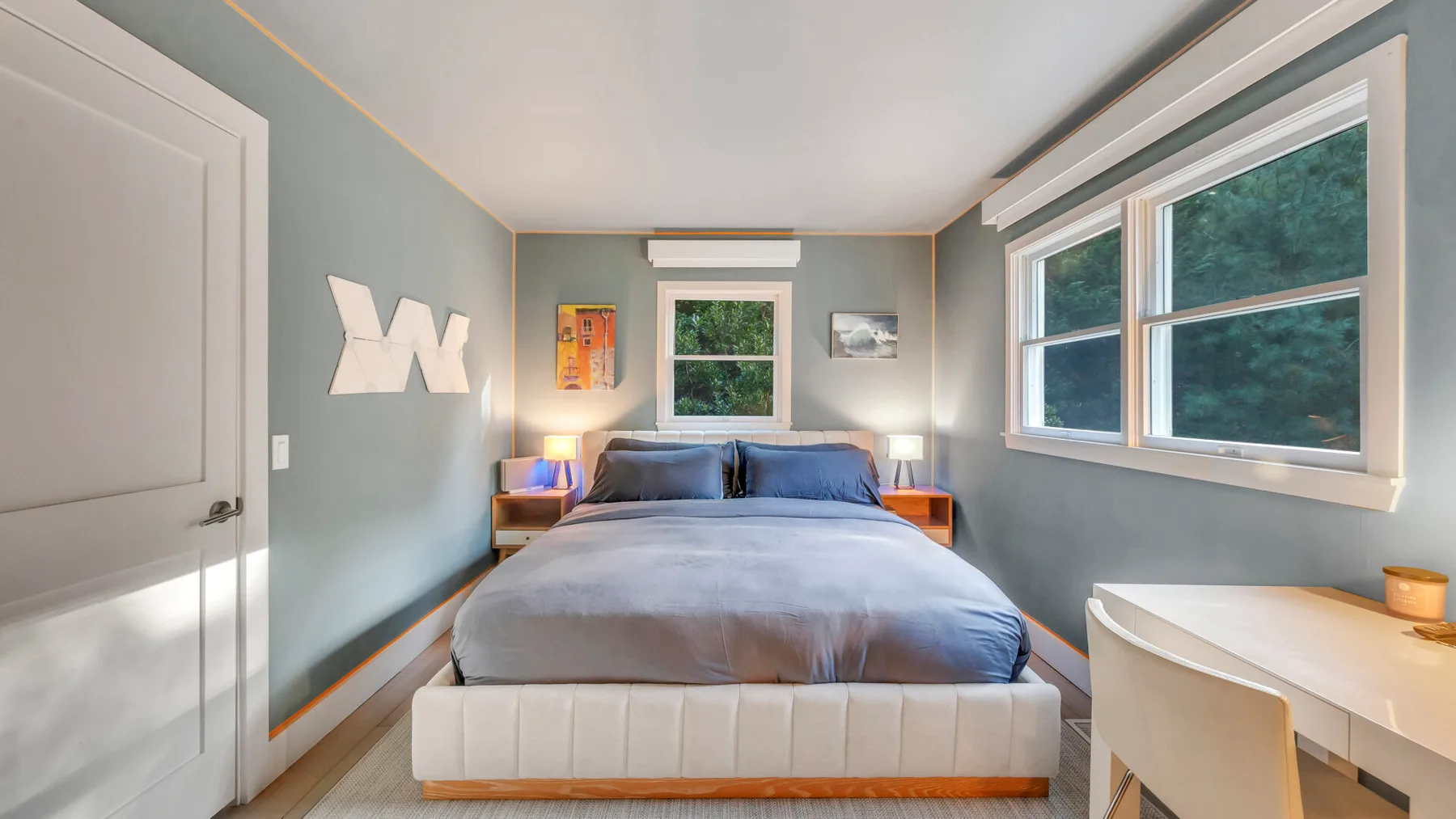 Un dormitorio con una cama y grandes ventanas con vistas a los árboles.