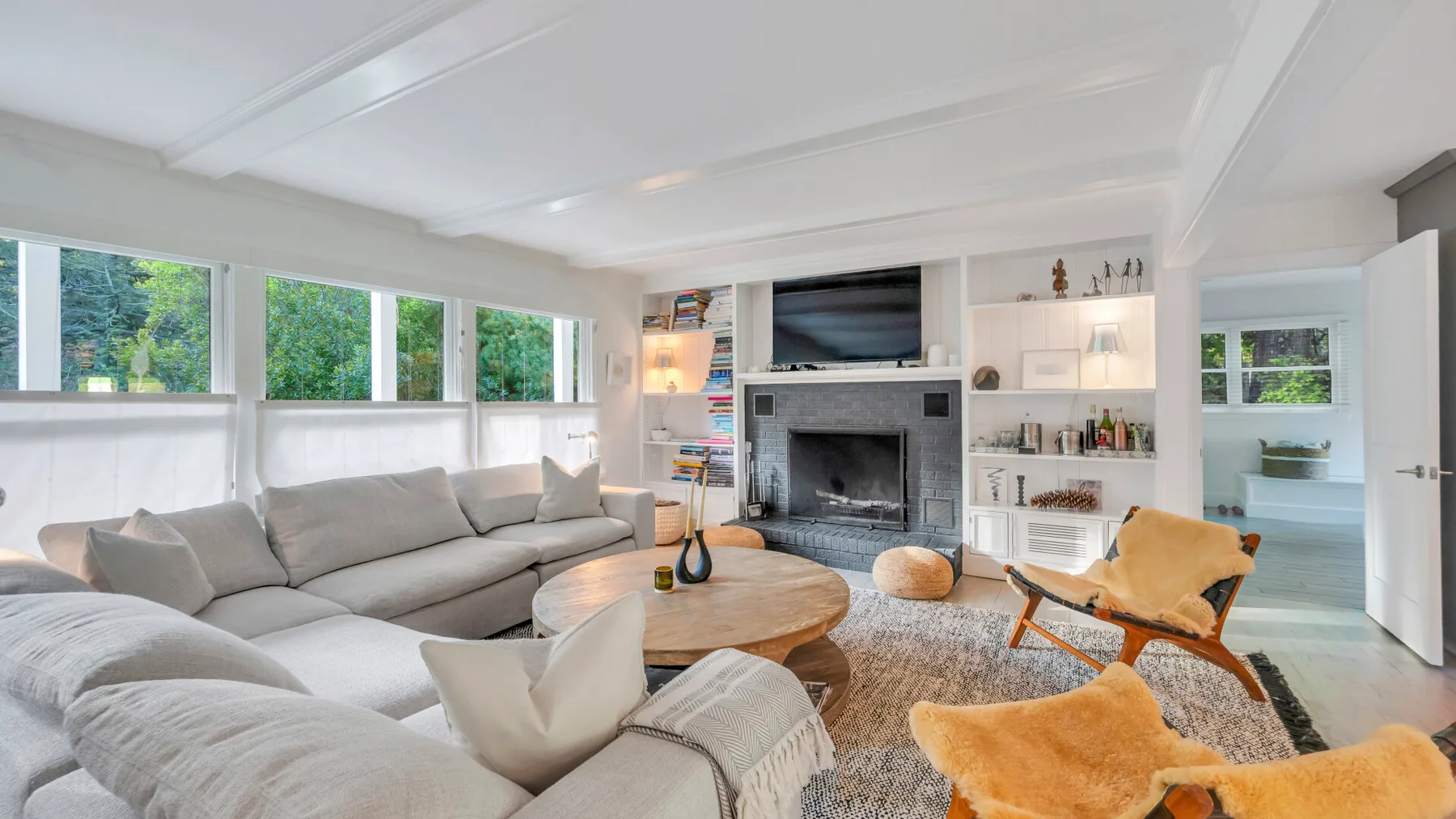 Una sala luminosa con sofá seccional, chimenea y estanterías empotradas.
