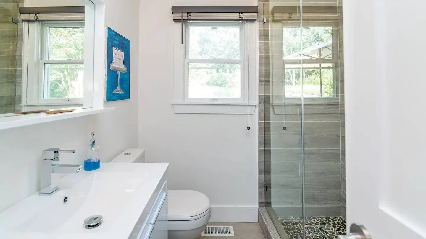 Un baño luminoso con un lavabo blanco y una ducha de vidrio.