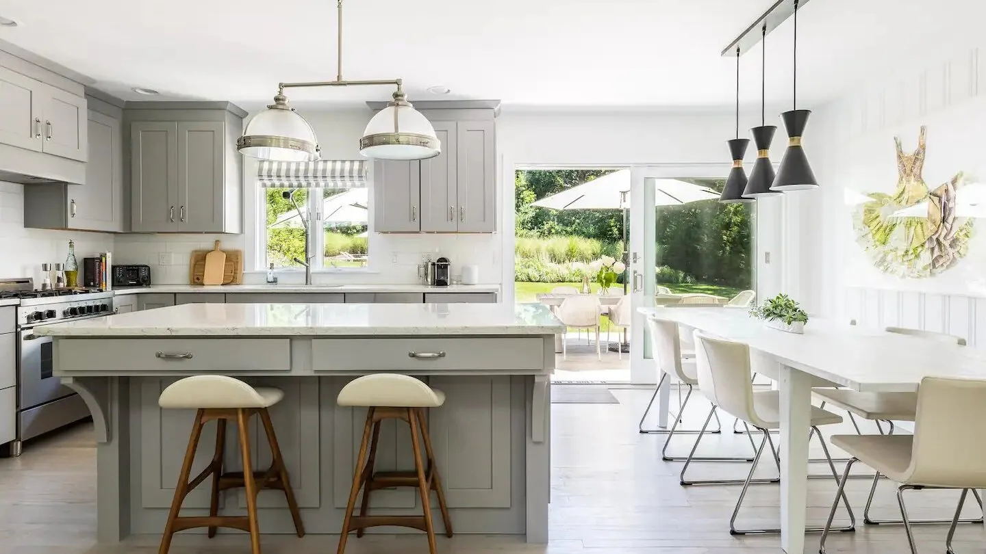 Una cocina y comedor luminosos con una isla grande y una mesa blanca.