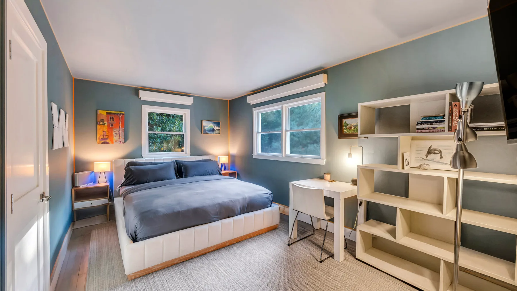 Un dormitorio con una cama, ventanas y estanterías abiertas.