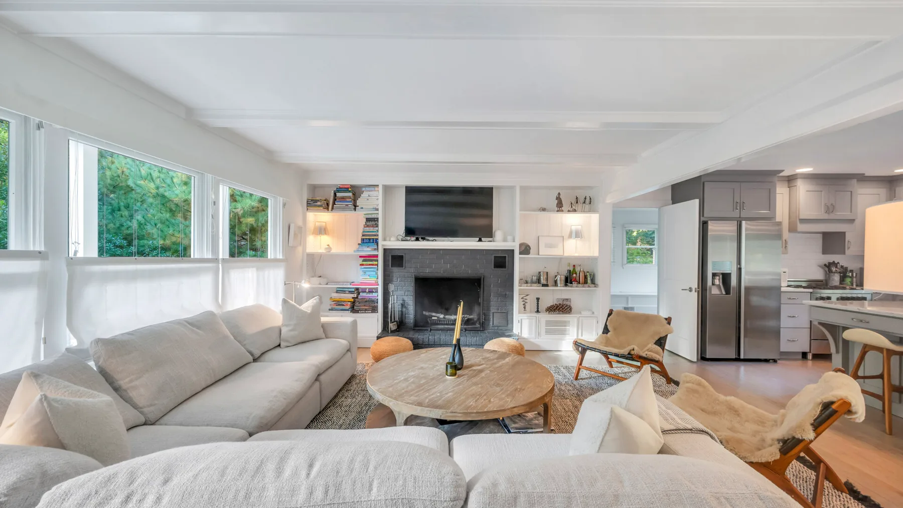 Una luminosa sala de estar de planta abierta con asientos, una mesa de centro redonda y una cocina.