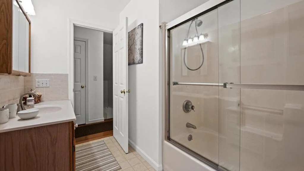 A bathroom with a vanity beside a glass-enclosed shower.