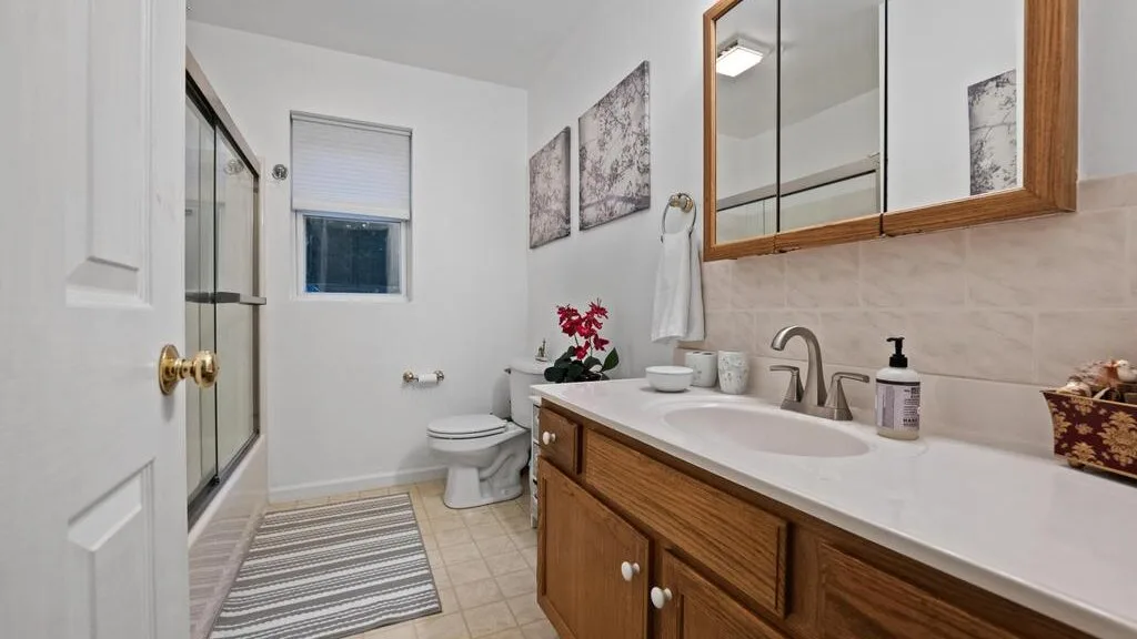 A bathroom with a long vanity, sink, mirror, and shower.