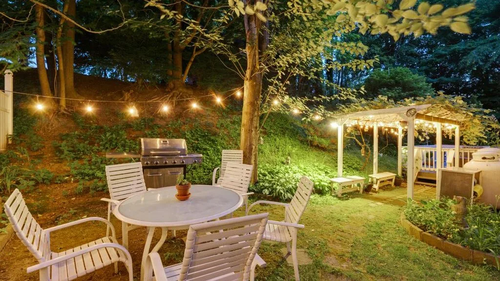 An outdoor garden seating area with string lights and a covered dining space.