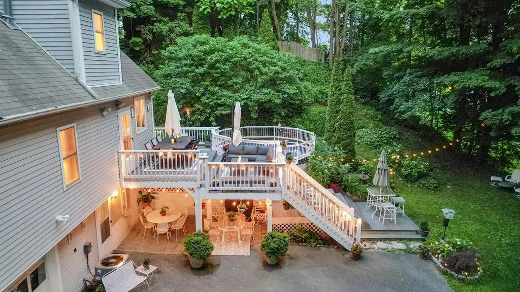 An outdoor deck and patio beside a house, with seating and trees.