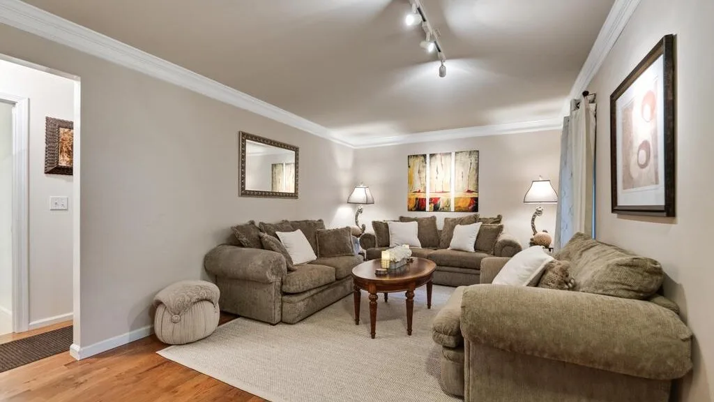 A living room with upholstered seating, a coffee table, and framed artwork.