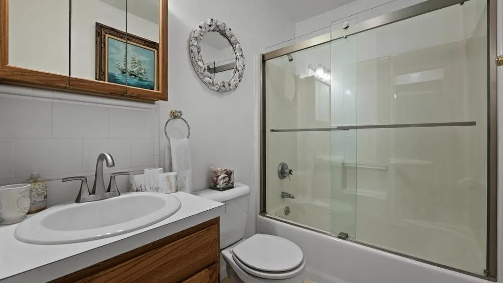 A bathroom with a sink, toilet, and glass shower enclosure.