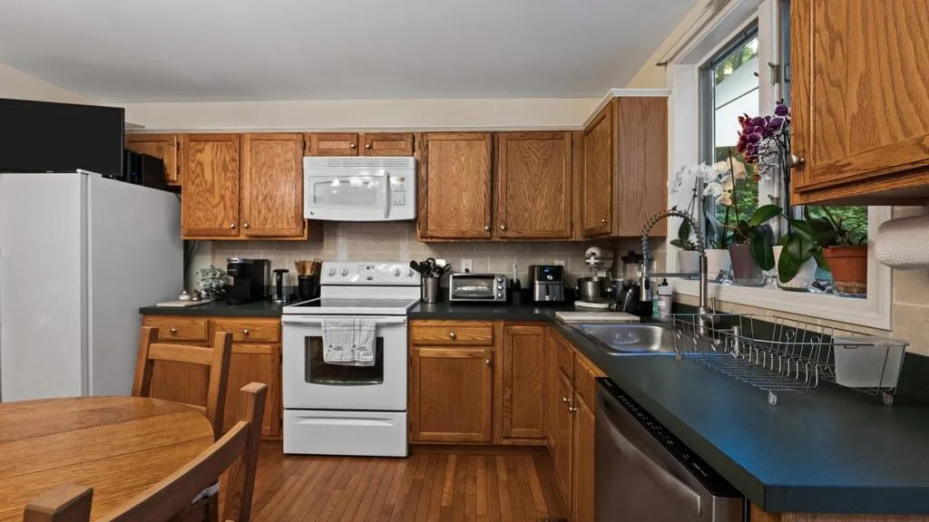 A kitchen with wooden cabinets, a stove, and dark countertops.