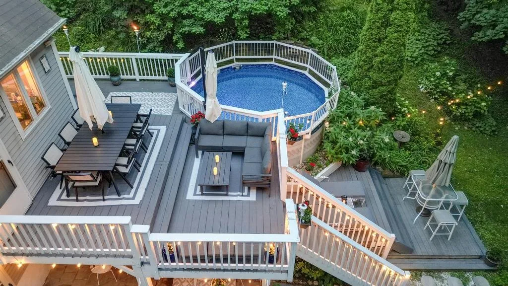 An elevated outdoor deck with seating and a small pool, surrounded by greenery.