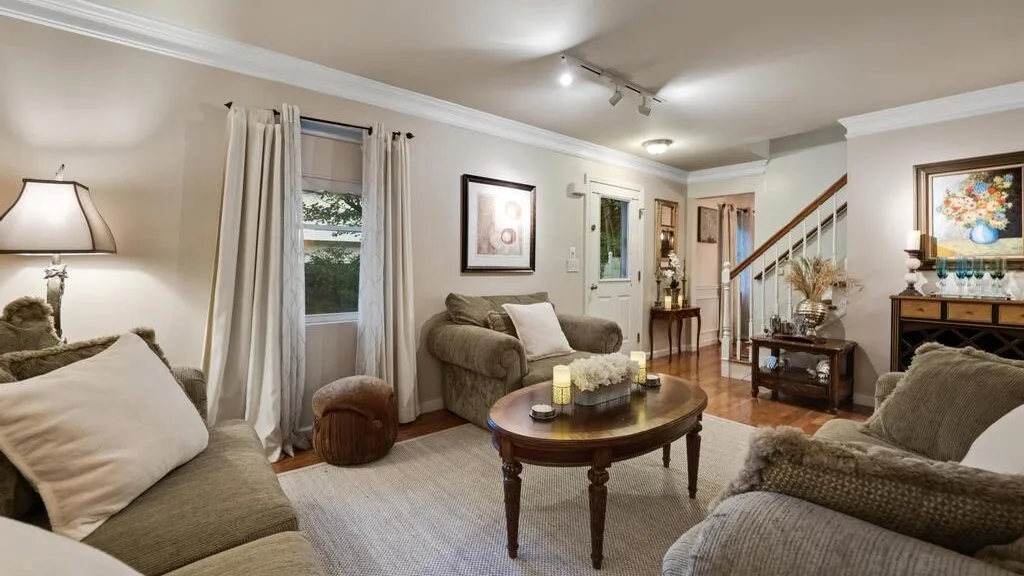 A living room with seating around a coffee table beside a staircase.