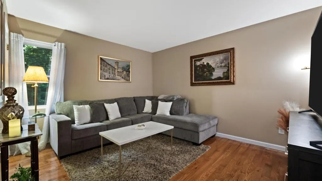 A living room with sectional seating, a coffee table, and framed wall art.