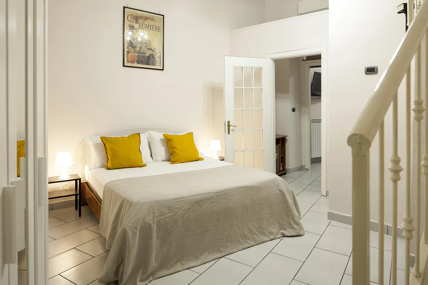 A bright bedroom with a neatly made bed and yellow pillows.