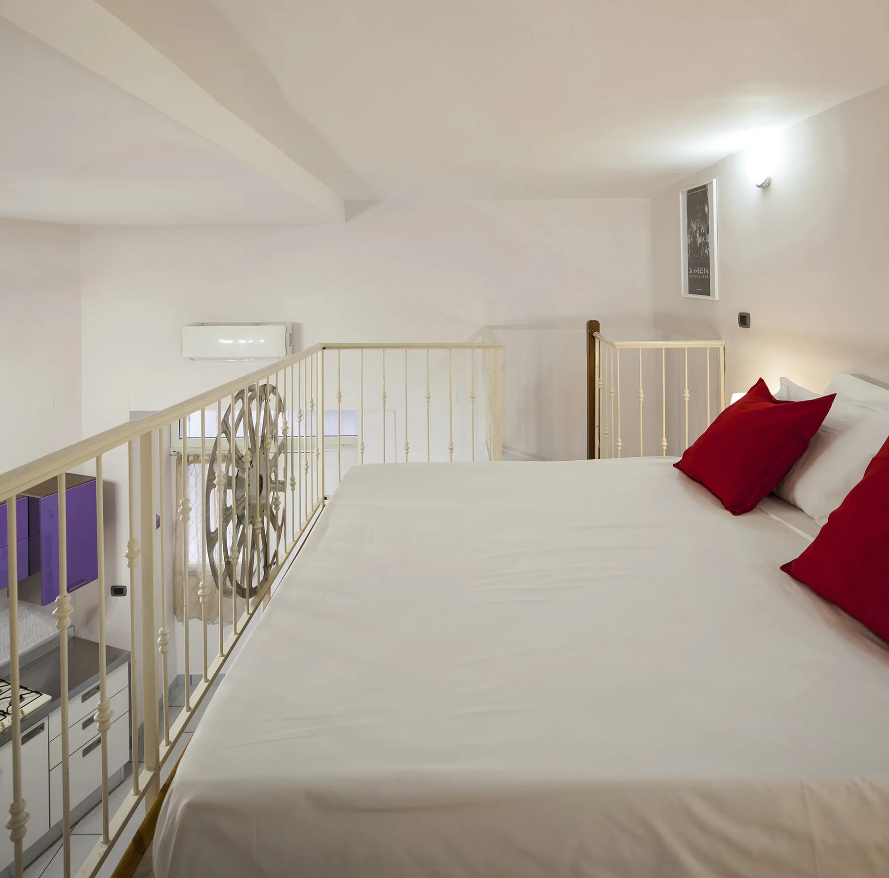 A bed fills a bright loft sleeping area, with a railing along the side.