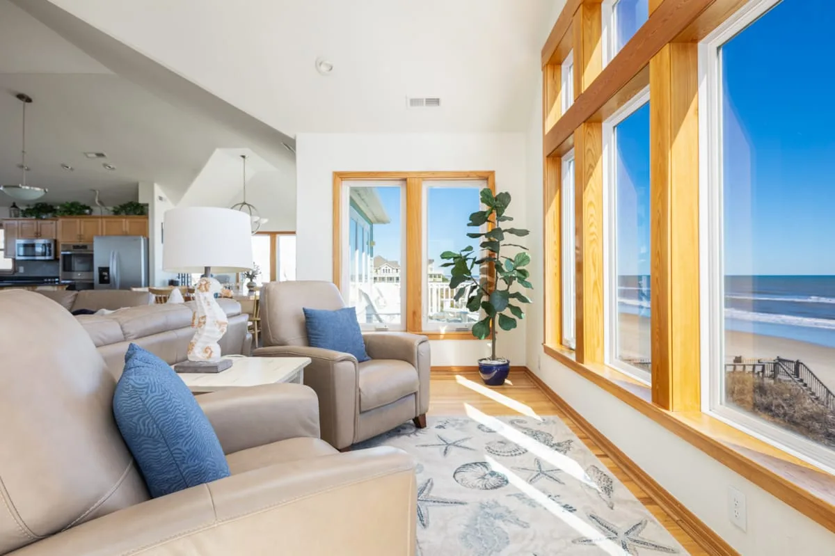 Una sala luminosa con asientos junto a grandes ventanas con vista al océano.