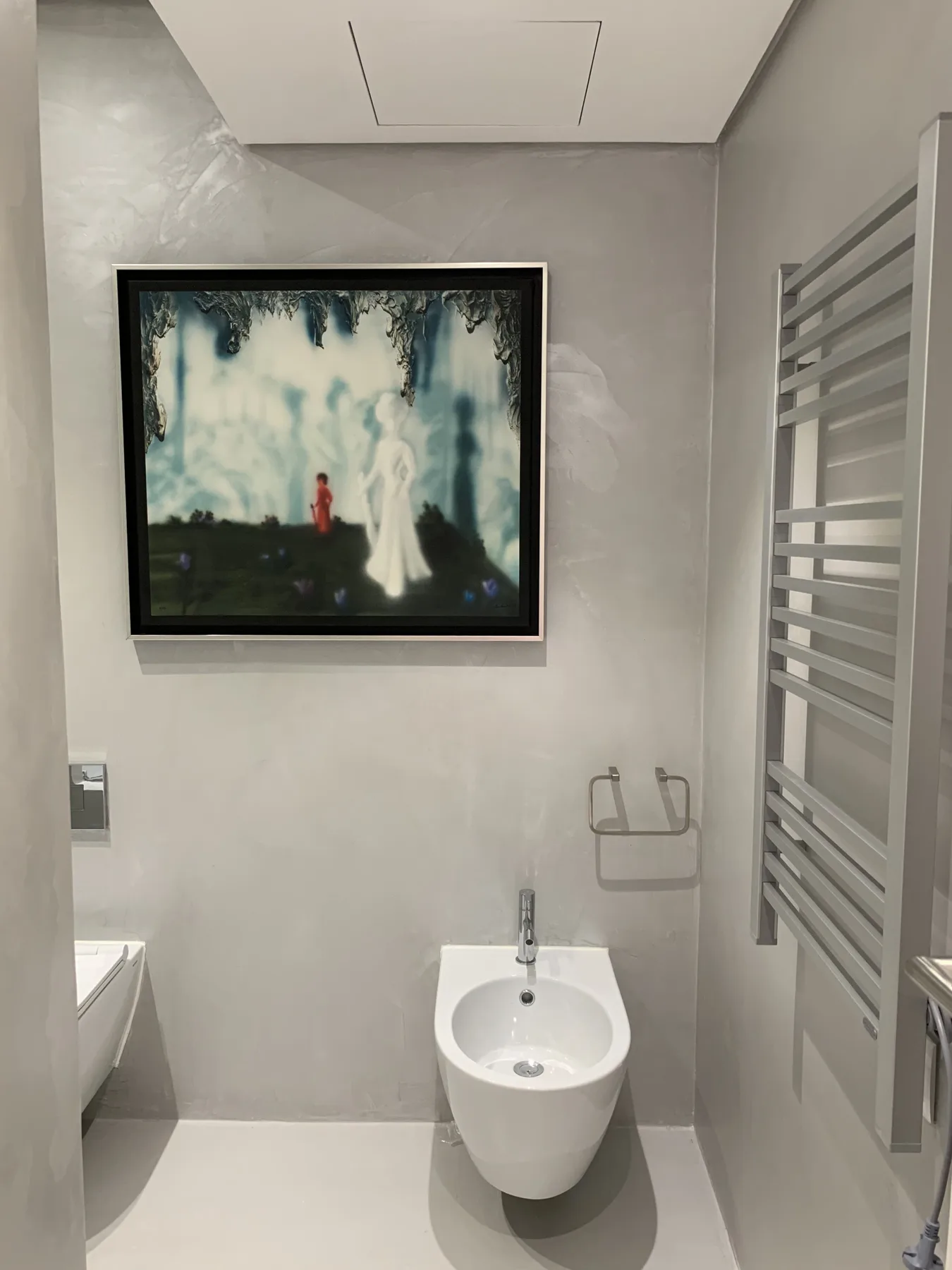Un baño moderno con bidé y un cuadro colgado en la pared.