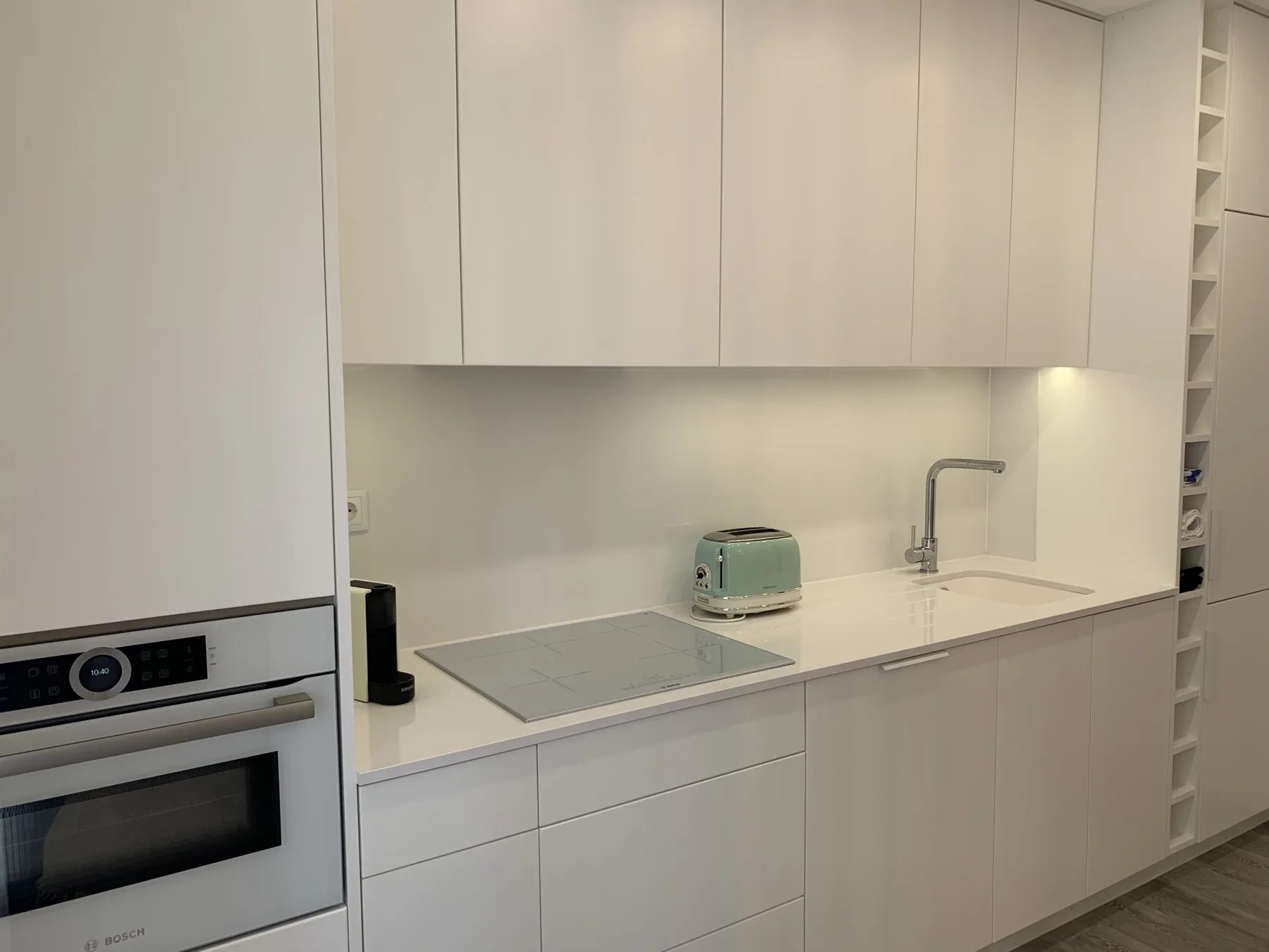 Una cocina moderna con armarios blancos, una encimera y un horno.