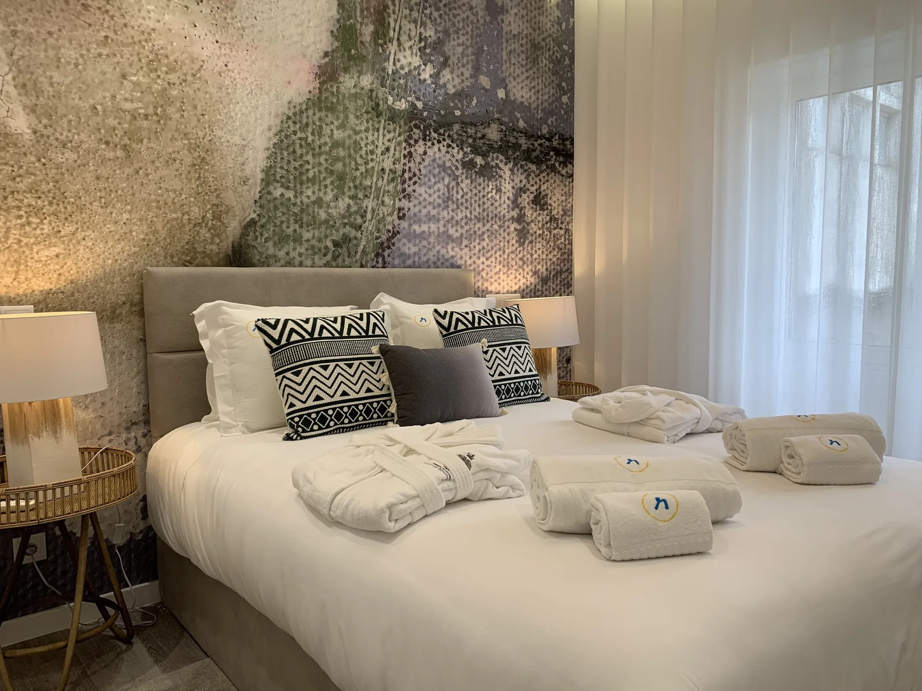 Un dormitorio con una cama bien hecha y cojines estampados.