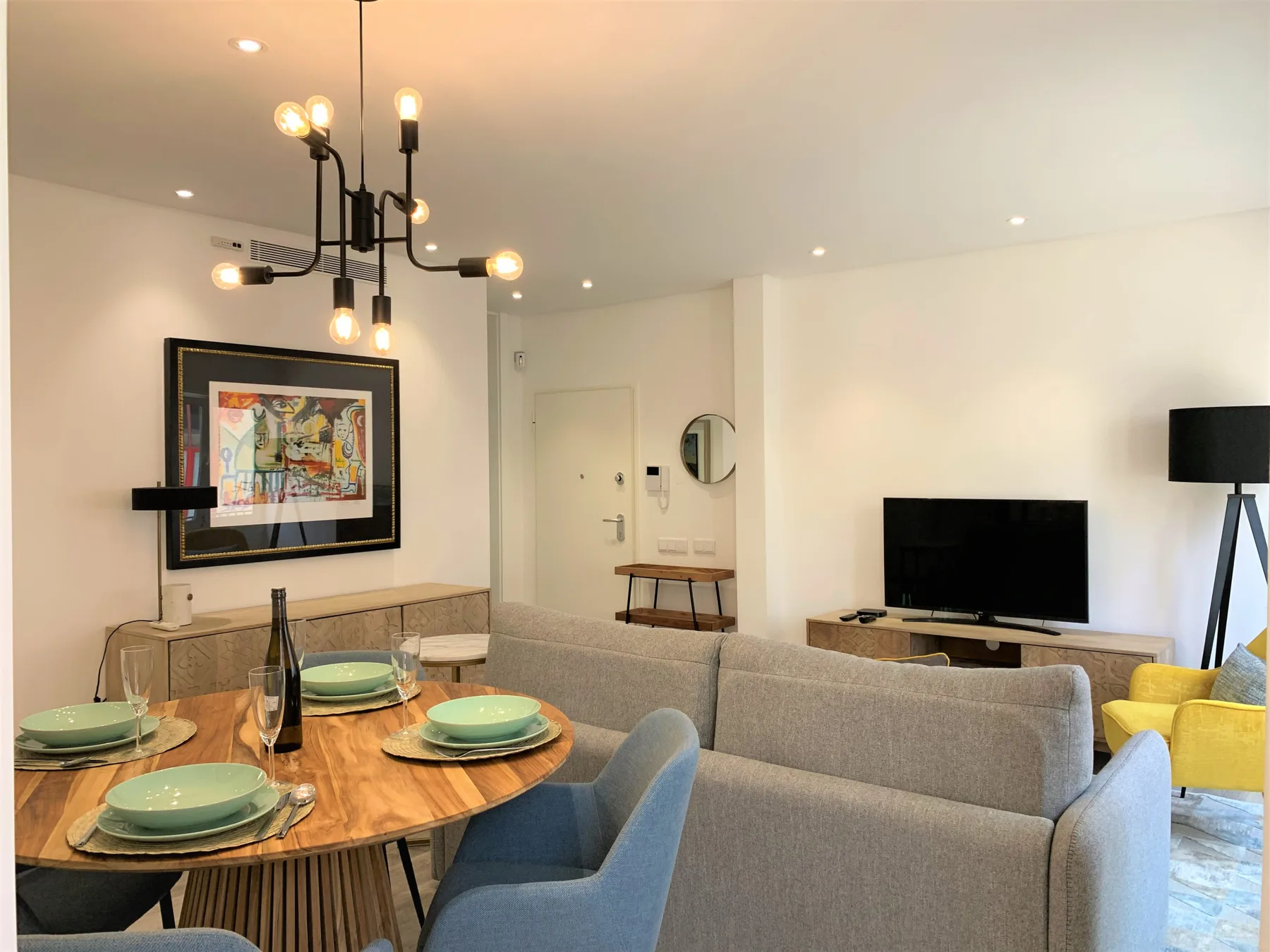 Sala de estar y comedor con la mesa puesta y asientos.