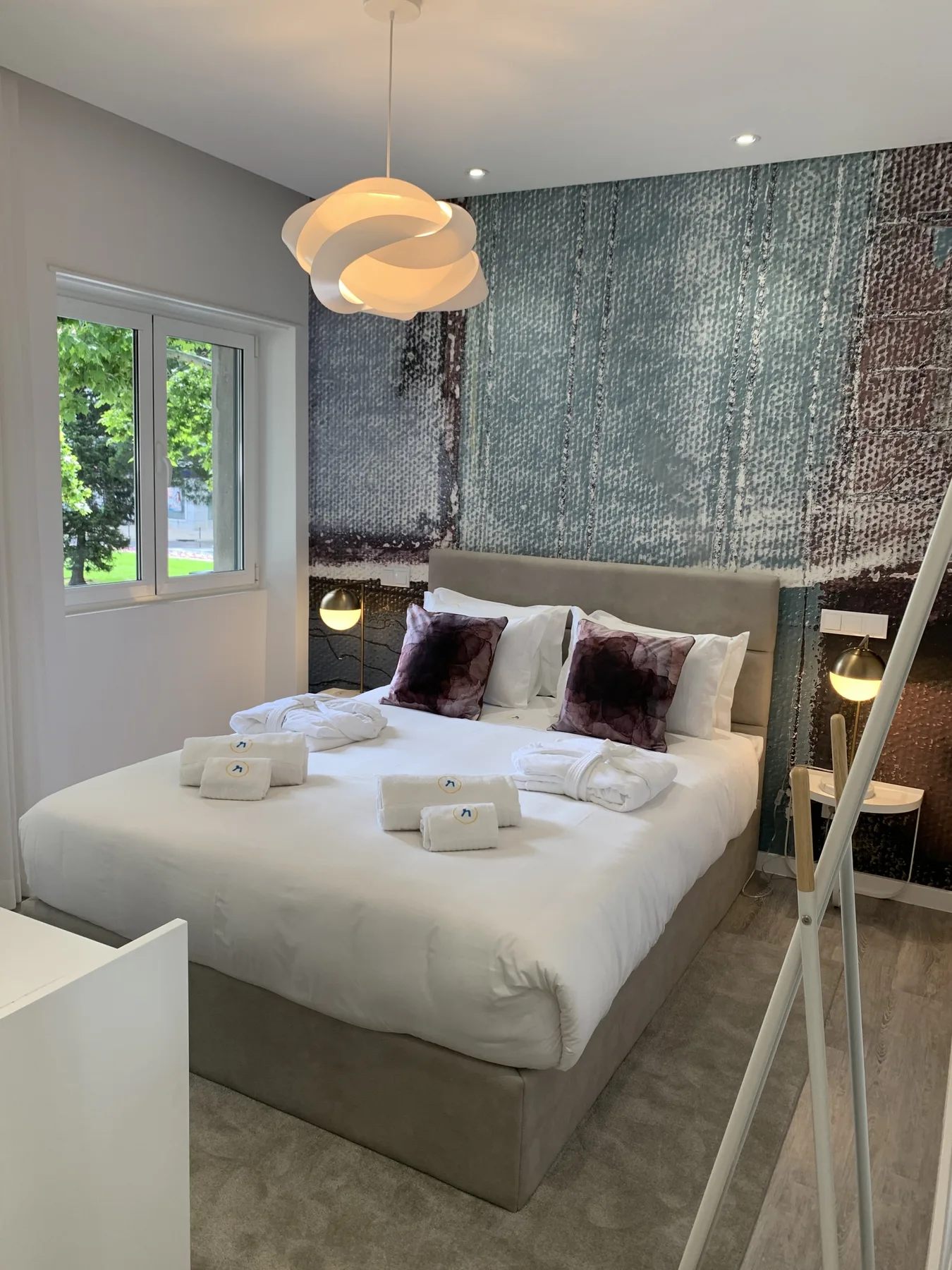 Un dormitorio con una cama bien hecha, cojines decorativos y una ventana.
