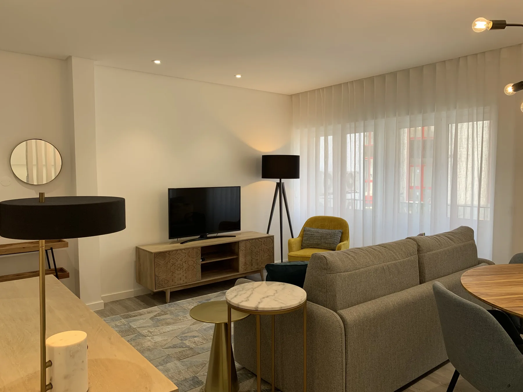 Una sala de estar con asientos, un televisor y cortinas translúcidas.