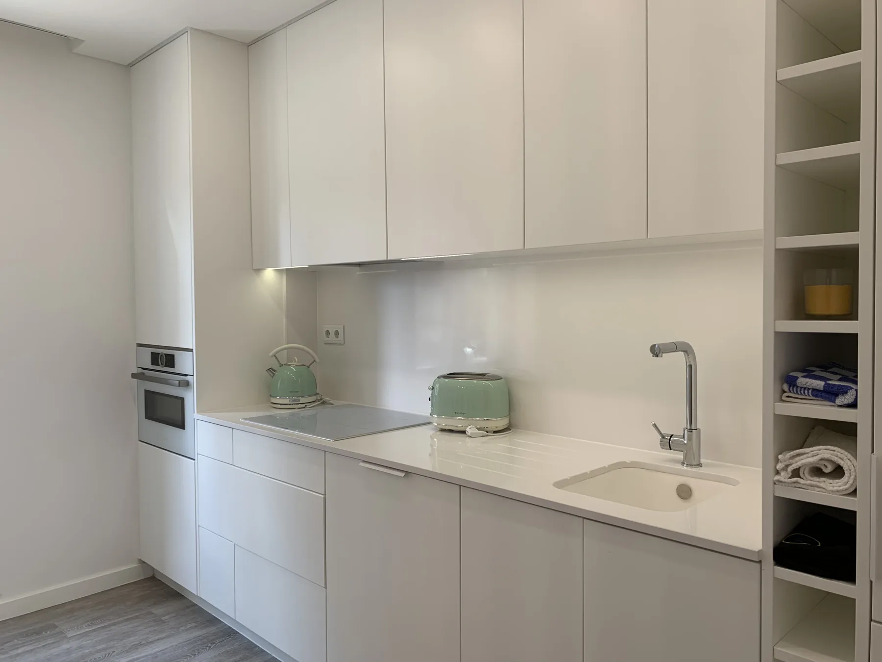 Una cocina luminosa y moderna con gabinetes blancos y un fregadero en la encimera.