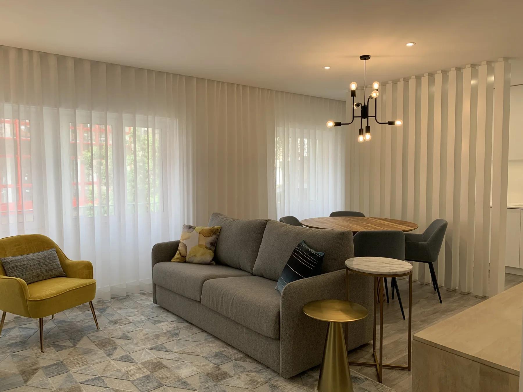 Una sala de estar y comedor con un sofá gris junto a una mesa redonda.