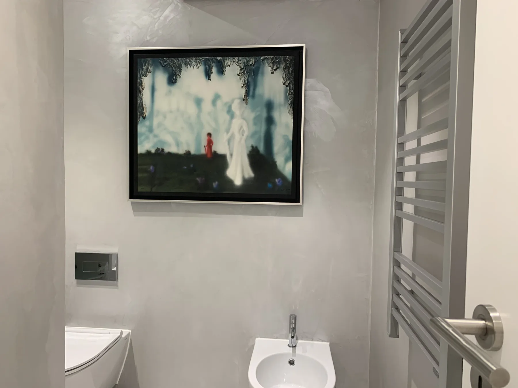 Un baño con una obra en la pared y un lavabo pequeño.