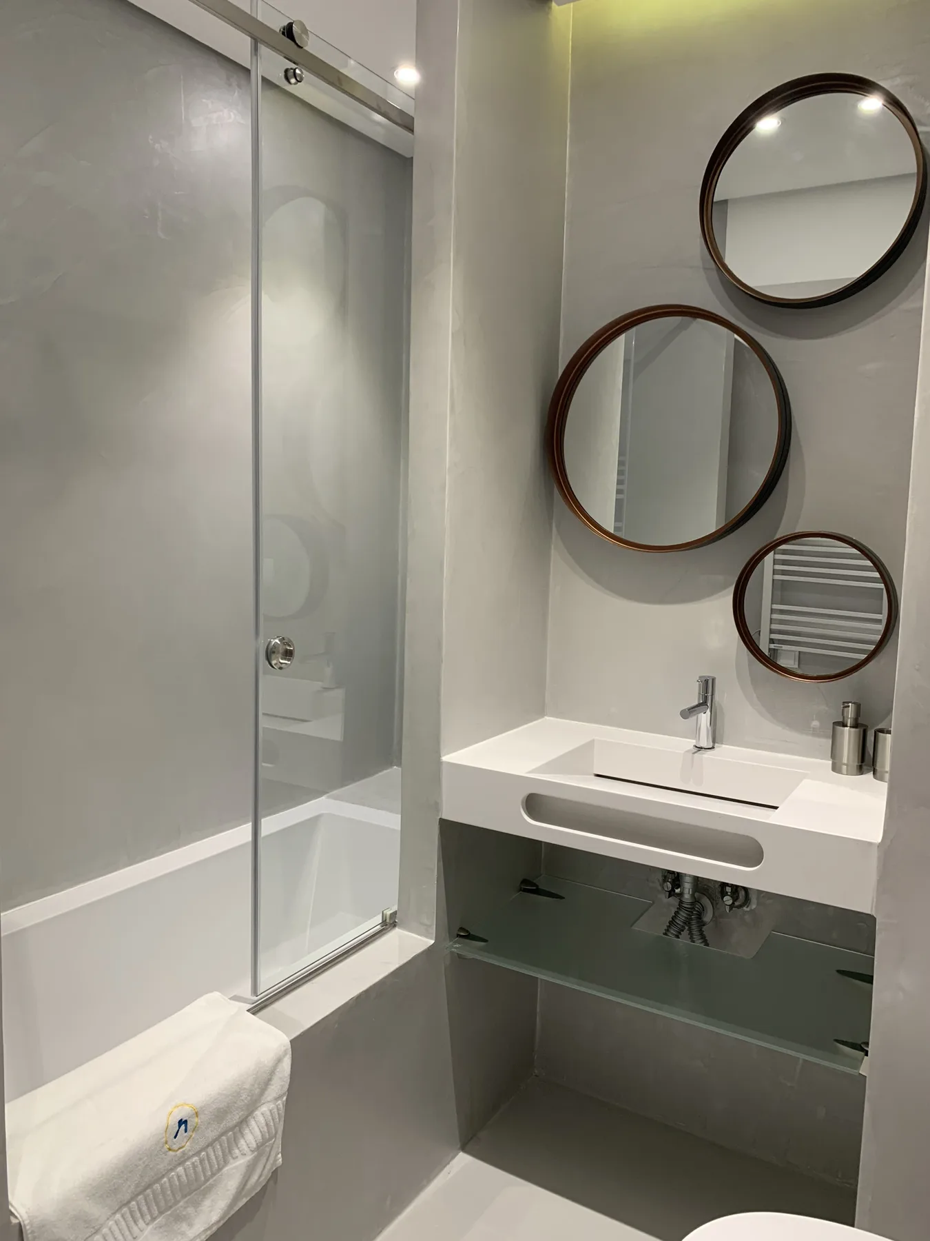 Un baño moderno con lavabo, espejos y una ducha con mampara de vidrio.