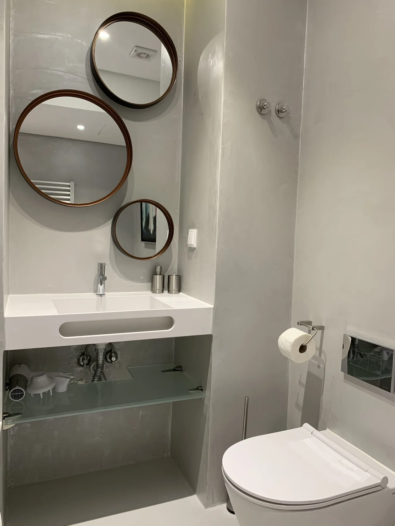 Un lavabo de baño con espejos redondos y un inodoro junto a la ducha.