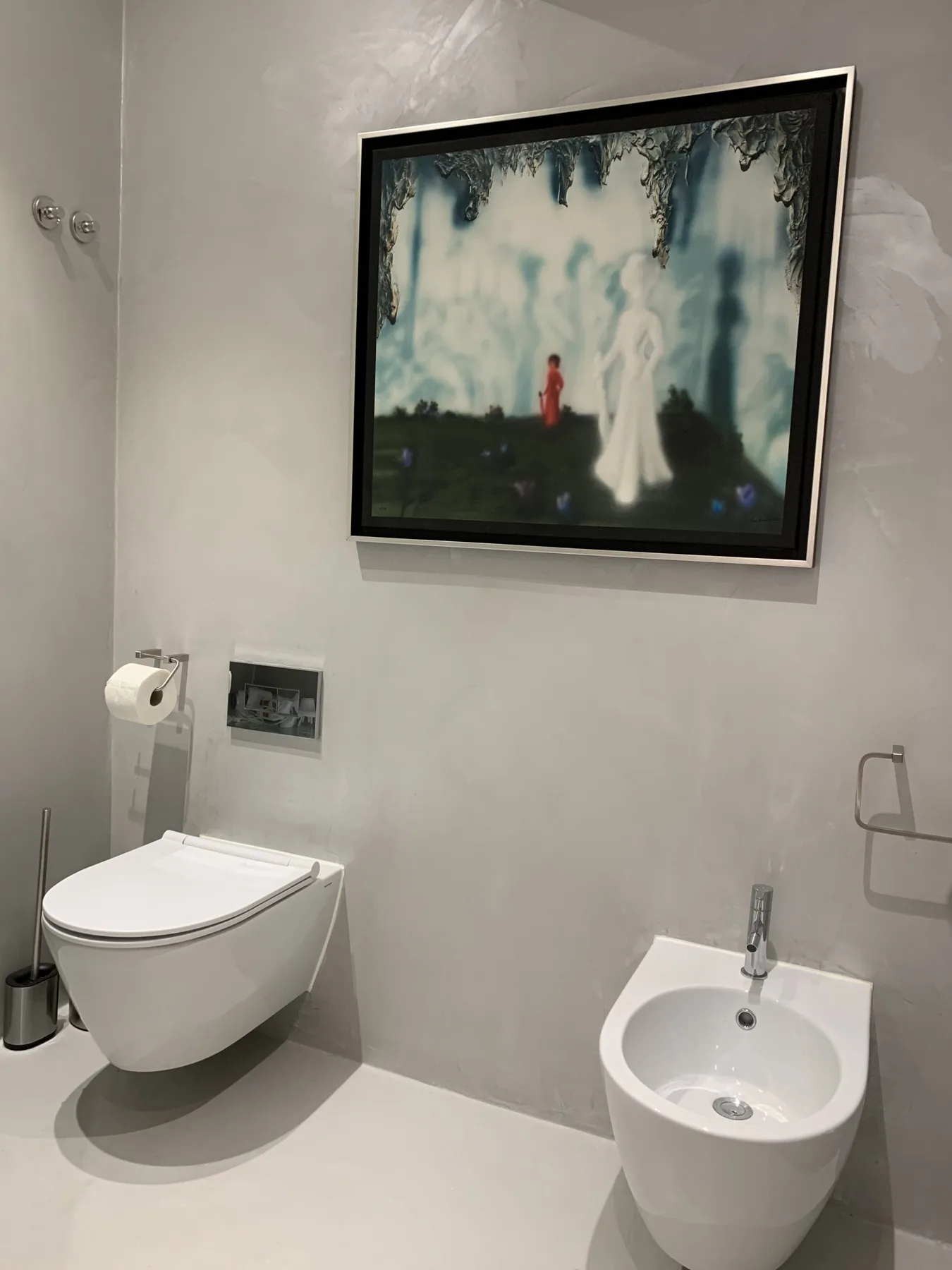 Un baño con un inodoro suspendido y un cuadro enmarcado.