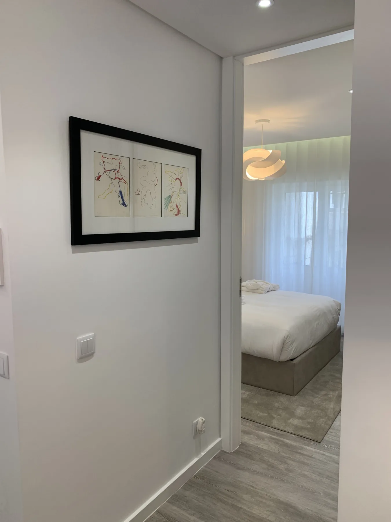 Se ve un dormitorio a través de una puerta, junto a un cuadro en la pared.