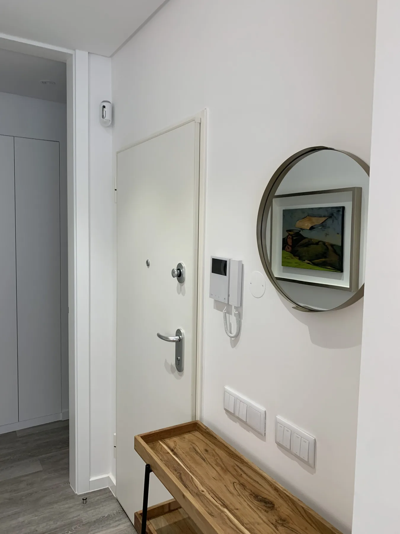 Una entrada luminosa con una mesa de madera y un espejo redondo en la pared.