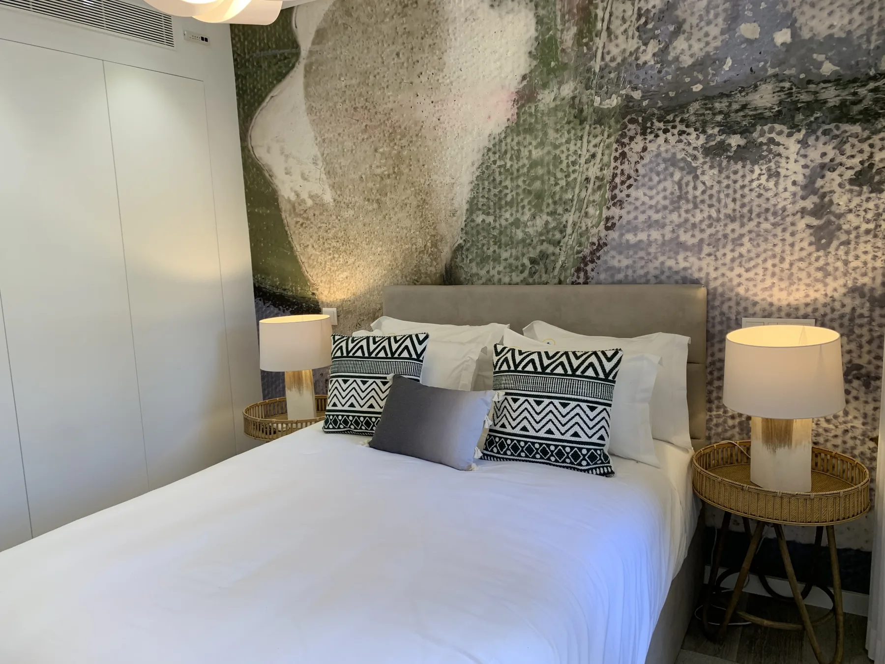 Dormitorio con una cama bien hecha y lámparas a ambos lados.
