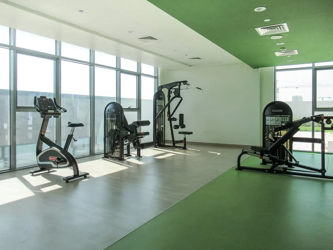 A gym with exercise equipment beside large windows.