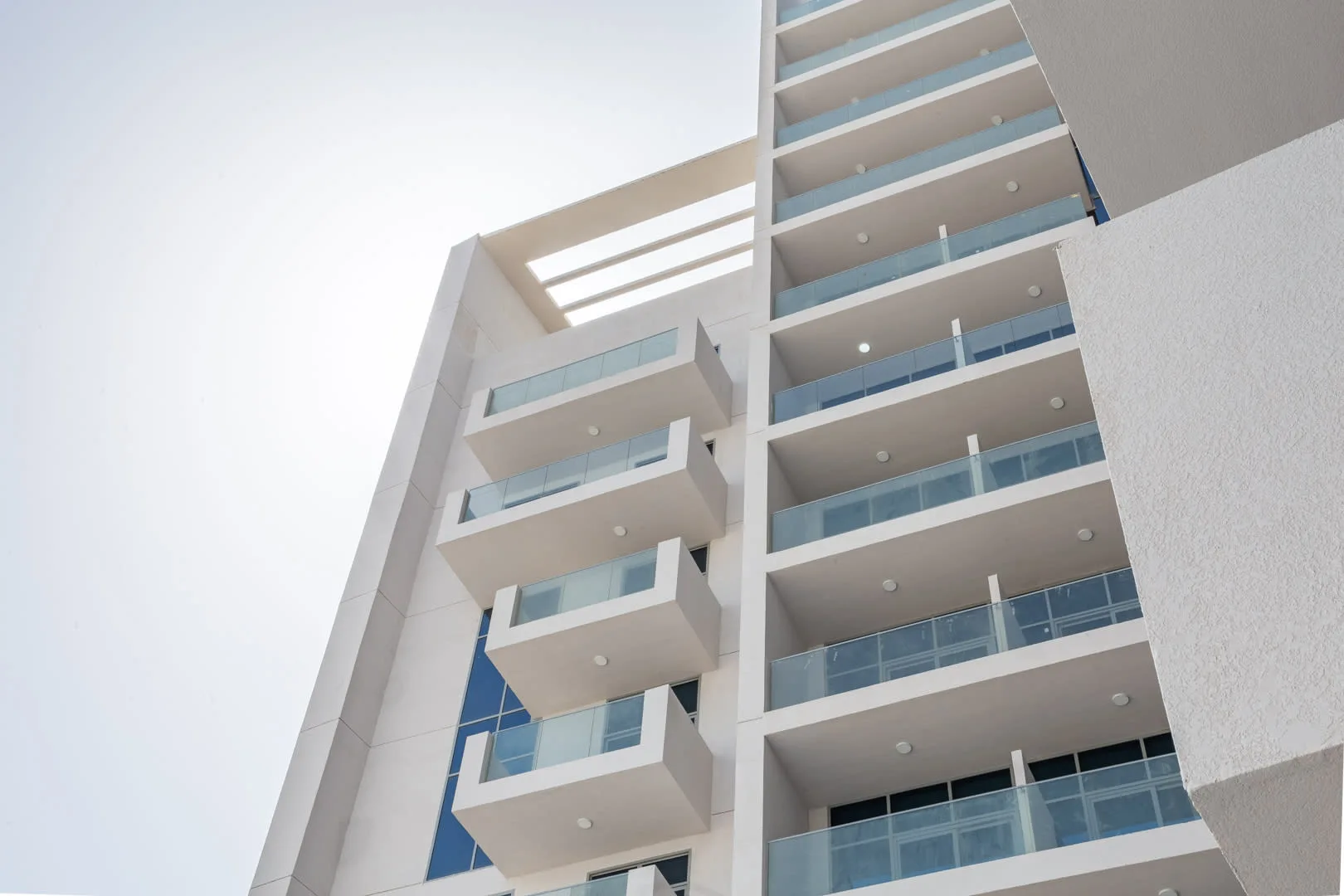 A modern high-rise building with stacked balconies and glass railings.