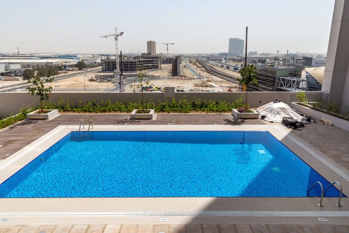 A rooftop swimming pool overlooks an urban construction site and railway tracks.
