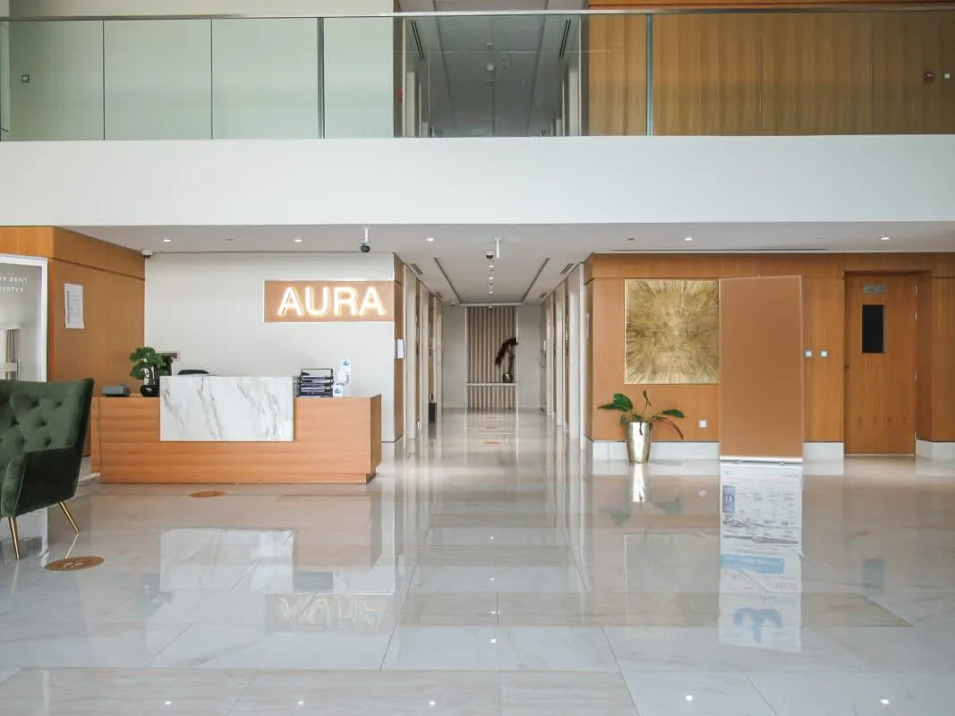 A modern reception lobby with a front desk and a hallway extending behind it.