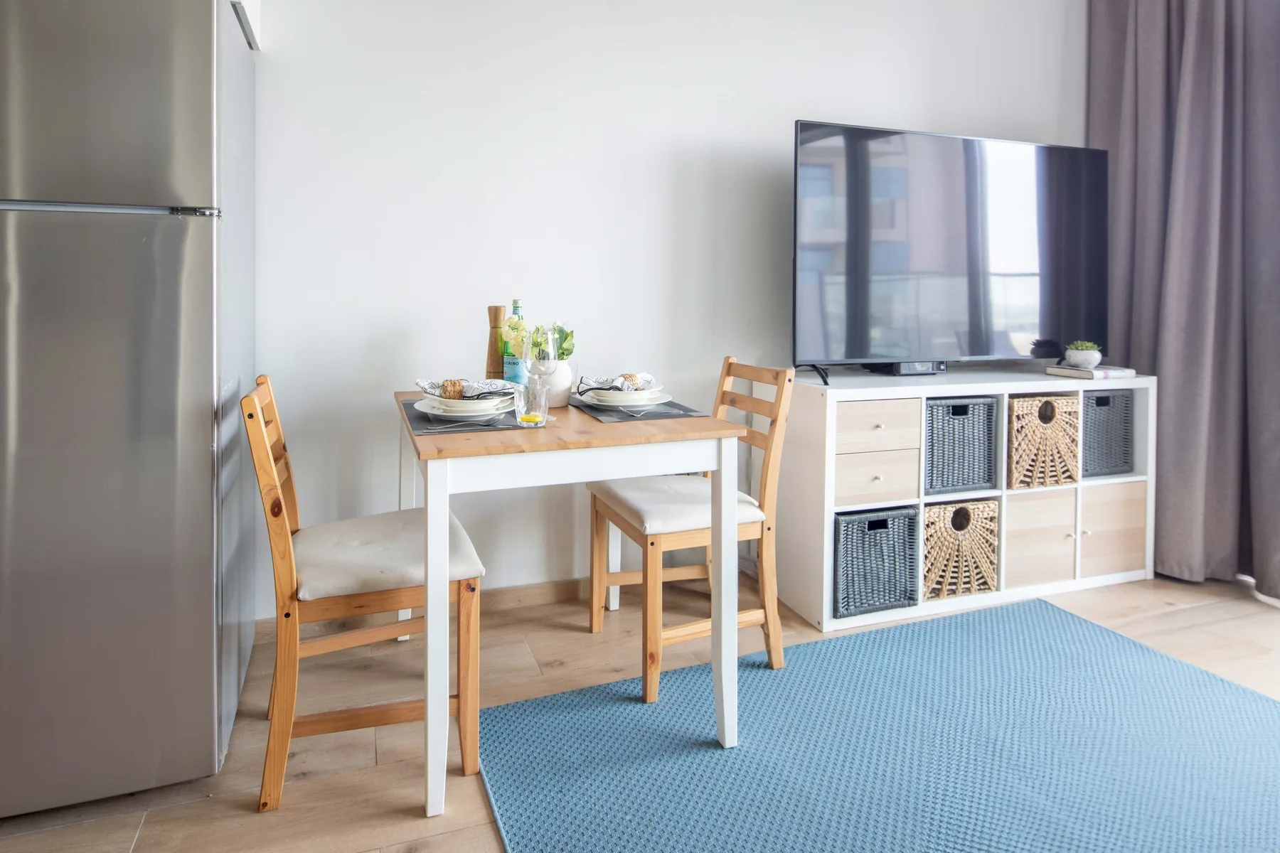 A dining area with a wooden table and chairs beside a television cabinet.