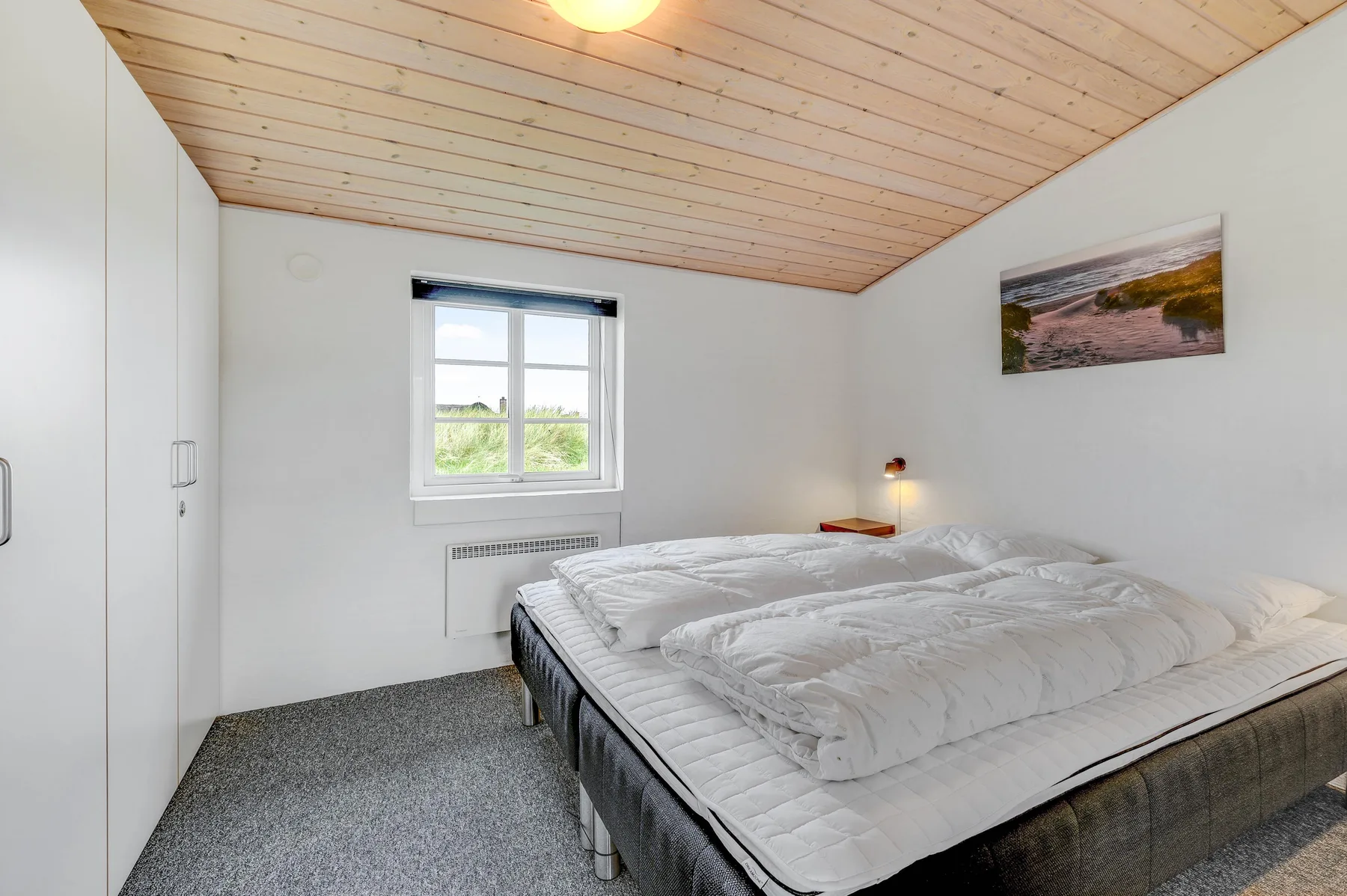 Un dormitorio con una cama grande, una ventana y un techo inclinado de madera.