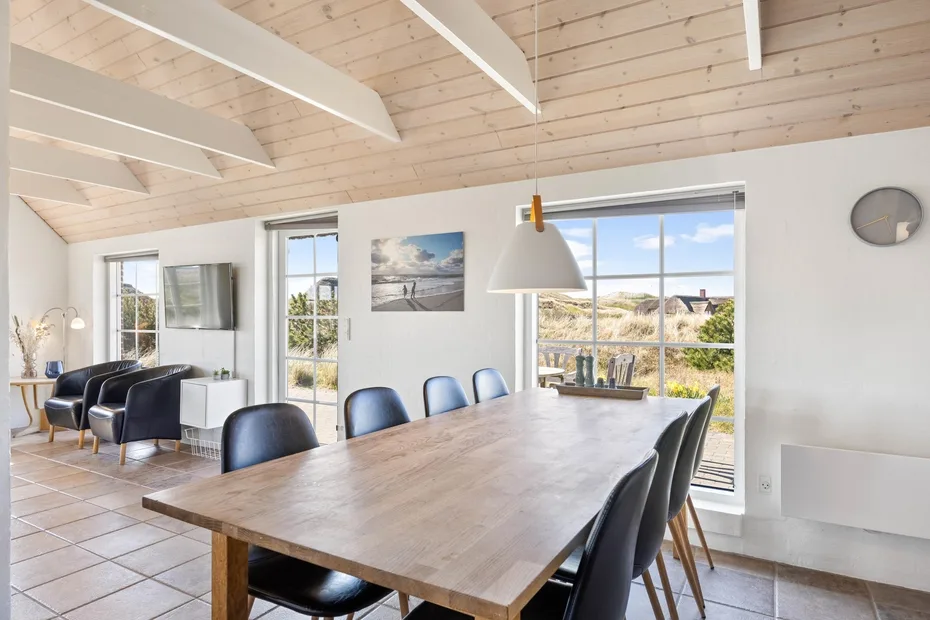 Un comedor luminoso con una mesa larga de madera junto a grandes ventanales.