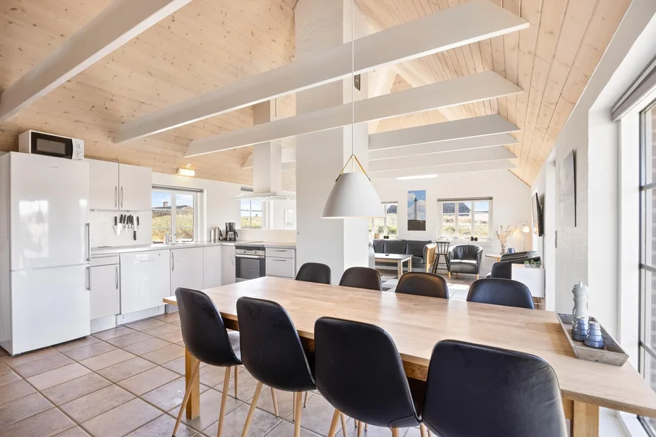 Una luminosa cocina y comedor de planta abierta con una mesa larga de madera y sillas oscuras.