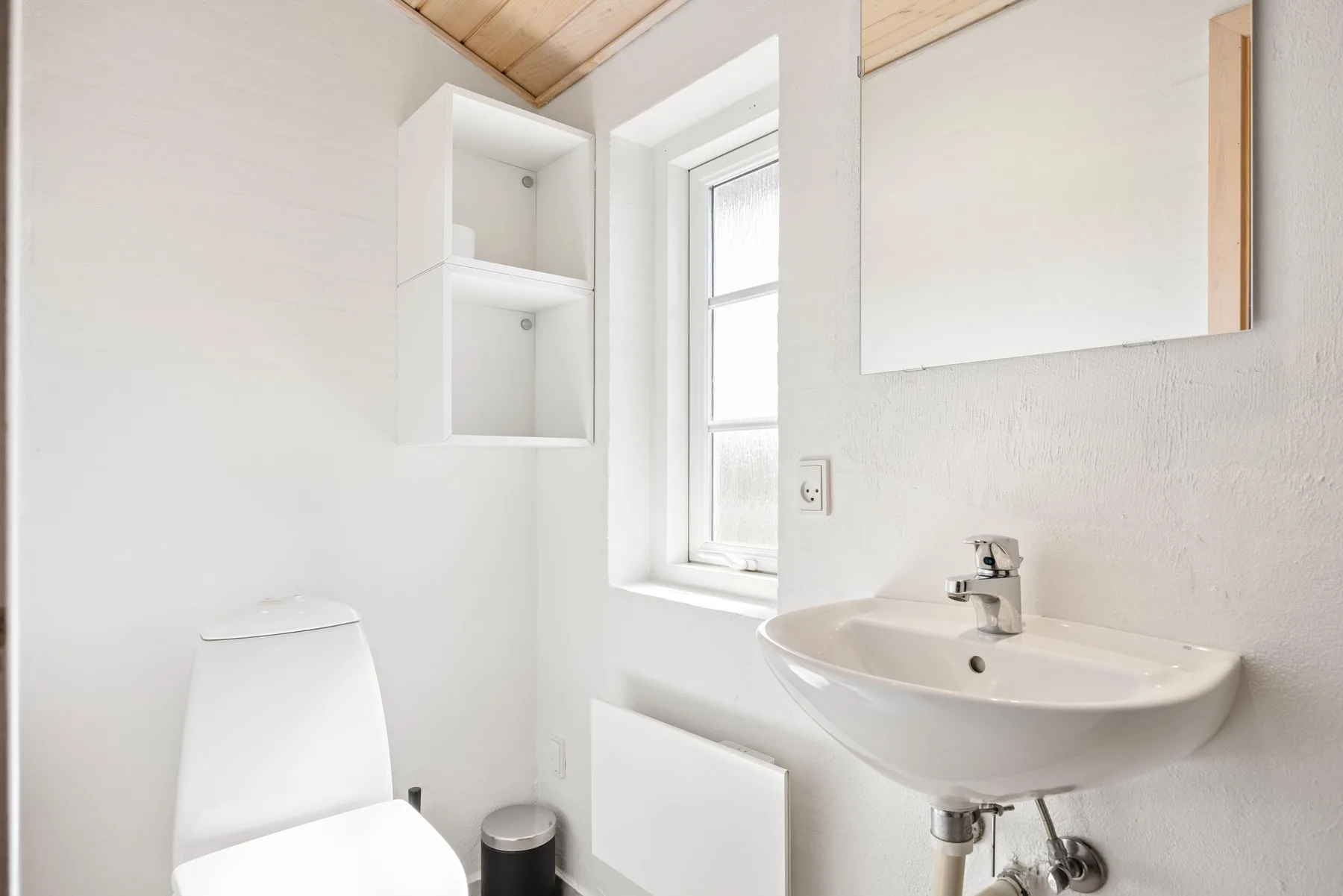 Un baño luminoso con lavabo, inodoro y ventana.