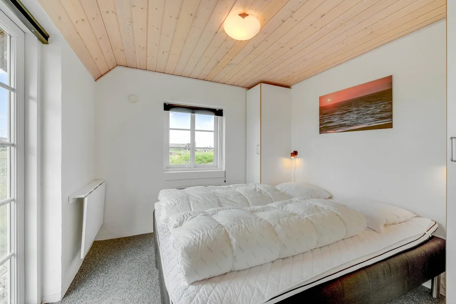 Un dormitorio con una cama grande bajo un techo inclinado de madera.
